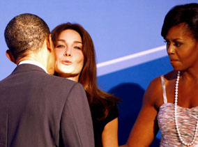 President Obama greets Carla Bruni, wife of French President Sarkozy, before the opening dinner for G20 leaders in Pittsburgh  – as US First Lady looks on (making you wonder a bit just how much trouble the President might be in later ... but not seriously, of course)!