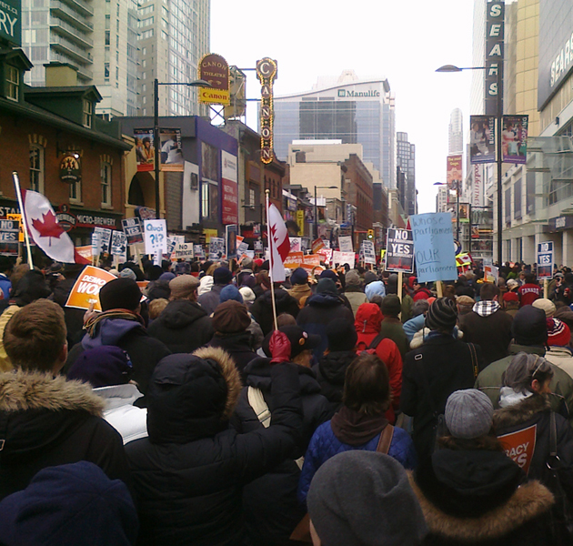 The crowd starts to move in Toronto, at last, led by police escort, inspired by drums, and chanting to keep warm. Photo WMW.