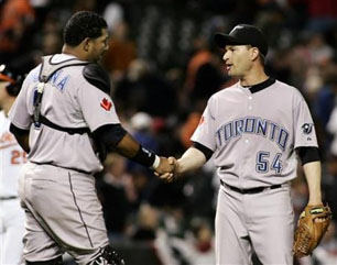 Jays catcher Jose Molina (l) congratulates relief pitcher Jason Frasor at the end of Jays’ April 10 win over Orioles. REUTERS/Joe Giza.