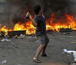 Red Shirt protester throws molotov cocktail in Bangkok, May 17. PAULA BRONSTEIN/GETTY.